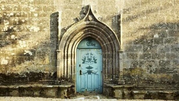 Un edificio de piedra con una puerta azul decorada con motivos florales.