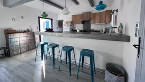 Une cuisine moderne avec un coin bar, des meubles en bois et des tabourets de bar bleus.