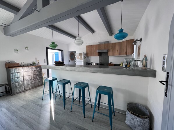 Una cocina moderna con barra, armarios de madera y taburetes azules.
