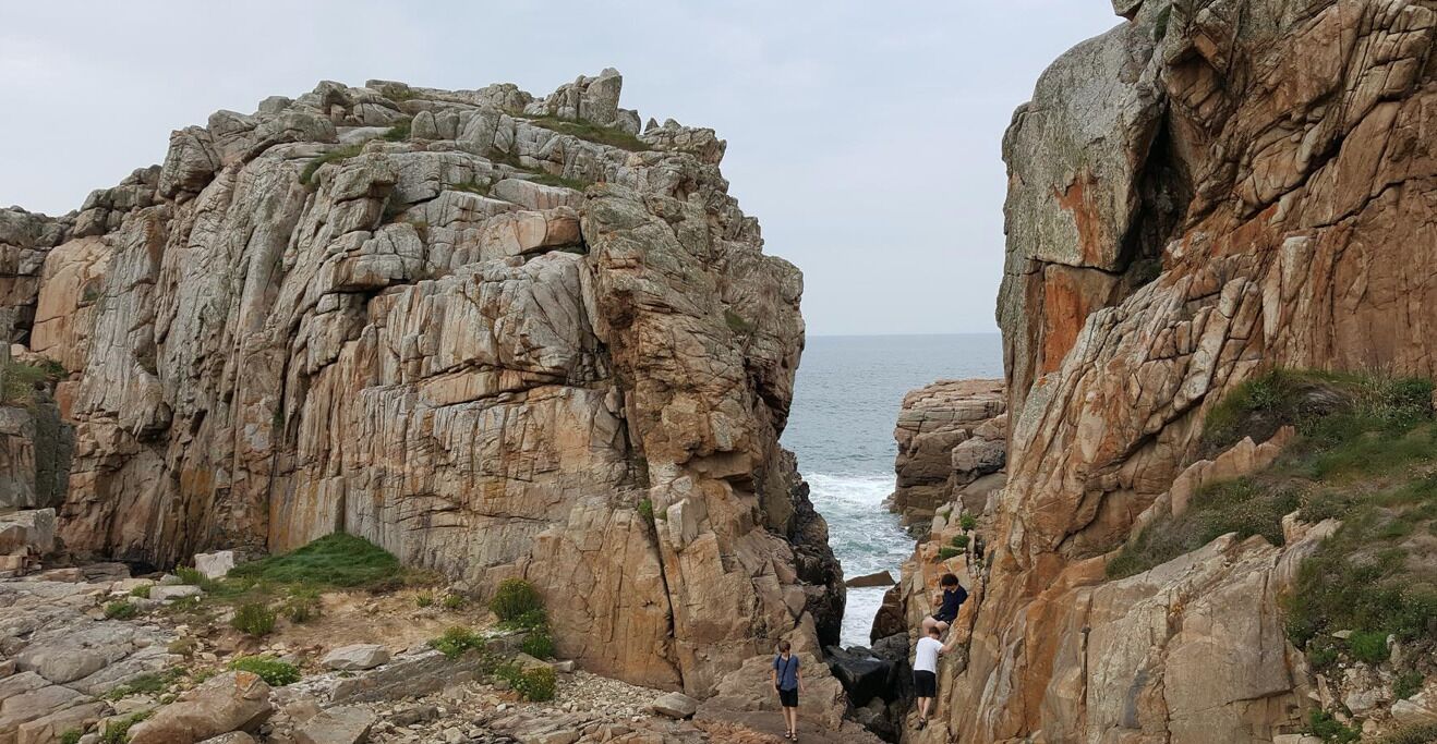 A rocky coastal landscape with a narrow passage between two large rock formations.