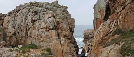 A rocky coastal landscape with a narrow passage between two large rock formations.