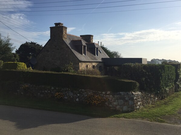 A stone house with a sloped roof, a chimney, and a stone wall surrounding the property. - Fisherman's house for rent, sea view, Brittany (Plougrescant)