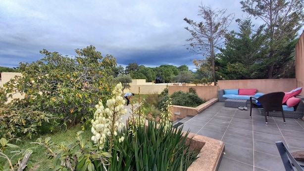 A rooftop garden with a seating area, including a sofa and chairs, surrounded by various plants and trees. - PROMOTION! A charming villa with a beautiful garden and a view of the mountains (Calenzana)