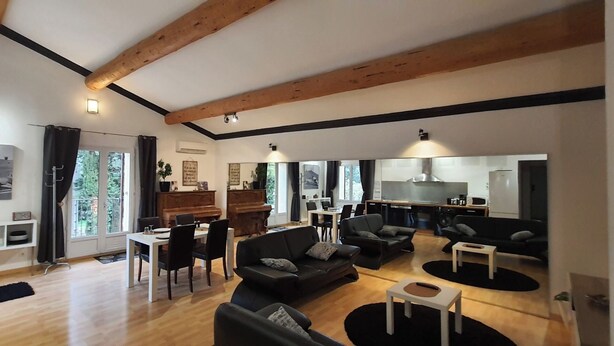 A spacious living area with a dining table, sofas, and a kitchen in the background.