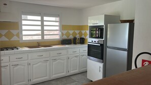 A kitchen with white cabinets, a stainless steel refrigerator, a microwave, and a stove.