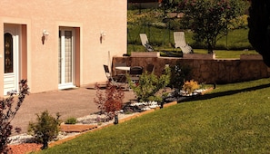 Un bâtiment doté d’un patio, d’un espace extérieur aménagé avec des sièges et d’un mur en pierre.