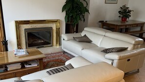 Un salon avec un canapé beige, une cheminée, une table basse et une plante en pot.