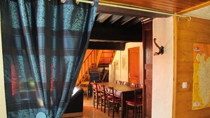 Ein Essbereich mit Holztisch und Stühlen, einer Karte an der Wand und einem teilweise geöffneten Vorhang.