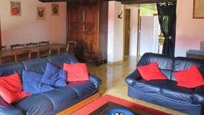Ein Wohnzimmer mit zwei blauen Ledersofas, roten Kissen, einem Holzespeisetisch mit Stühlen und einem roten Teppich.