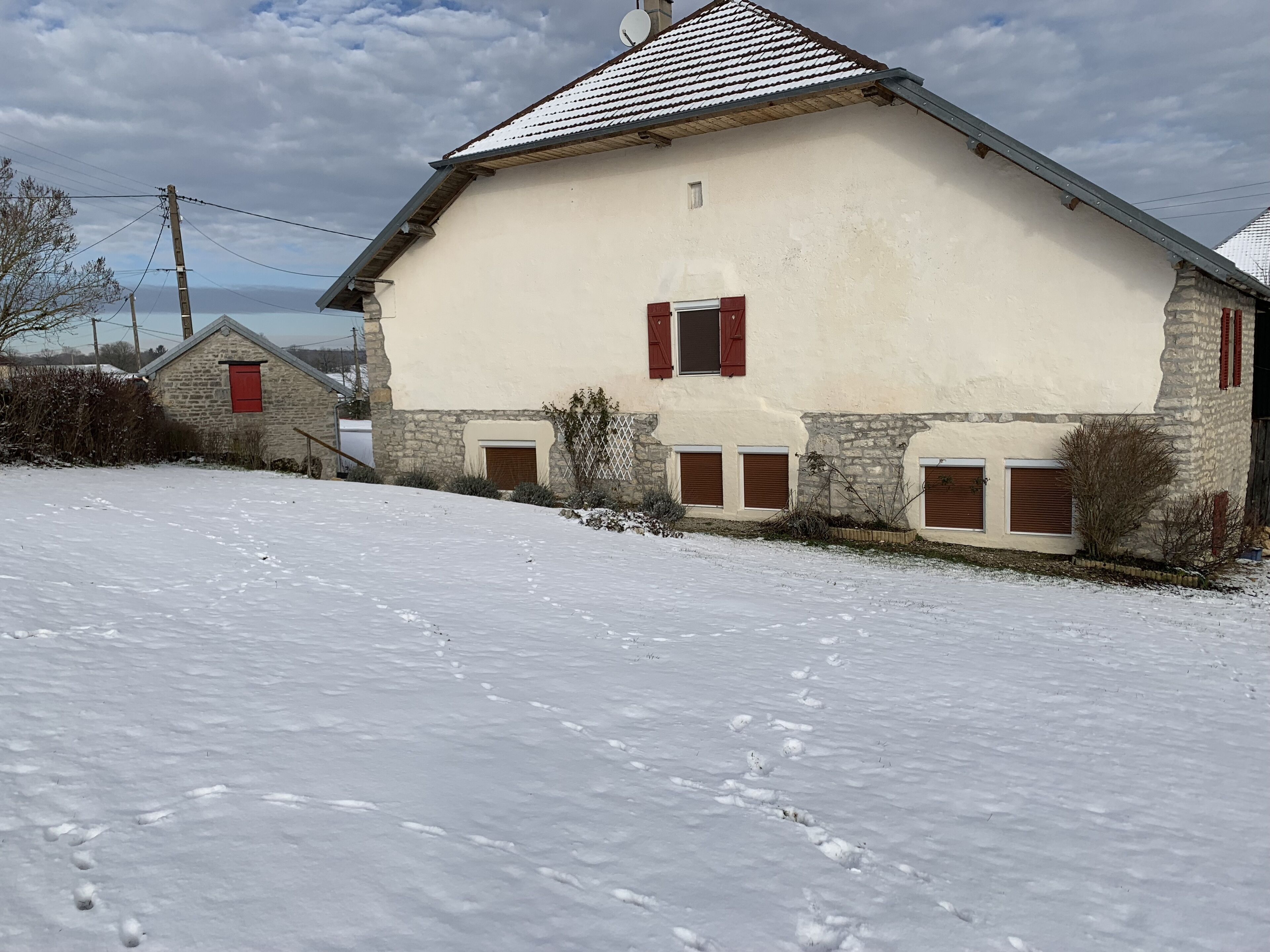 Ein eingeschossiges Gebäude mit geneigtem Dach, Stein Fundament und roten Fensterläden.