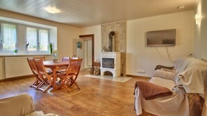 Un vaste espace de vie doté d’un plancher en bois, d’une cheminée, d’une table à manger avec des chaises et d’un canapé.