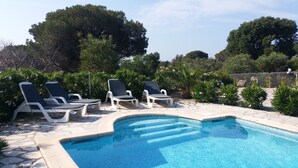 Una piscina amb terrassa de pedra, envoltada de gandules blanques i vegetació abundant.