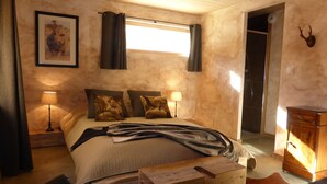 Un dormitorio acogedor con cama, dos lámparas, un cuadro enmarco, un mueble de madera y una decoración de cabeza de venado.