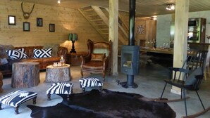 Un interior rústico con techo de madera, chimenea de piedra, zona de comedor y espacio de estar acogedor con alfombra de cuero de vaca.