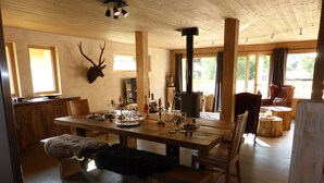 Interior de madera con una mesa de comedor dispuesta para una comida, una chimenea y una cabeza de ciervo montada.
