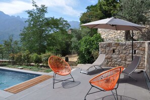 A poolside area with two orange chairs, a lounge chair, and a large umbrella. - RENOVATED BERGERIE CLIMATISEE PANORAMIC VIEW POOL HEATED BEACHES A 12MN (Montegrosso)