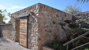Ein Steinhaus mit einer Holztür und einer Metalltreppe.