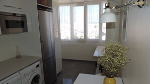 Une cuisine compacte équipée d’un lave-linge, d’un réfrigérateur et d’un coin repas avec une table et un vase de fleurs.