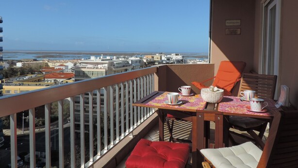 Un balcon avec une table, des chaises et une vue sur la ville et la mer.