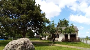 Une cabane rustique dotée d’une terrasse en bois et d’un grand rocher au premier plan.