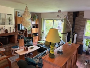 Ein Wohnzimmer mit Kamin, Fernseher, einer Couch und einem Essbereich mit Tisch und Stühlen.
