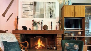A cozy living room with a fireplace, a television, and a bookshelf. - Peaceful house between sea and forest near Perros-Guirec (Louannec)