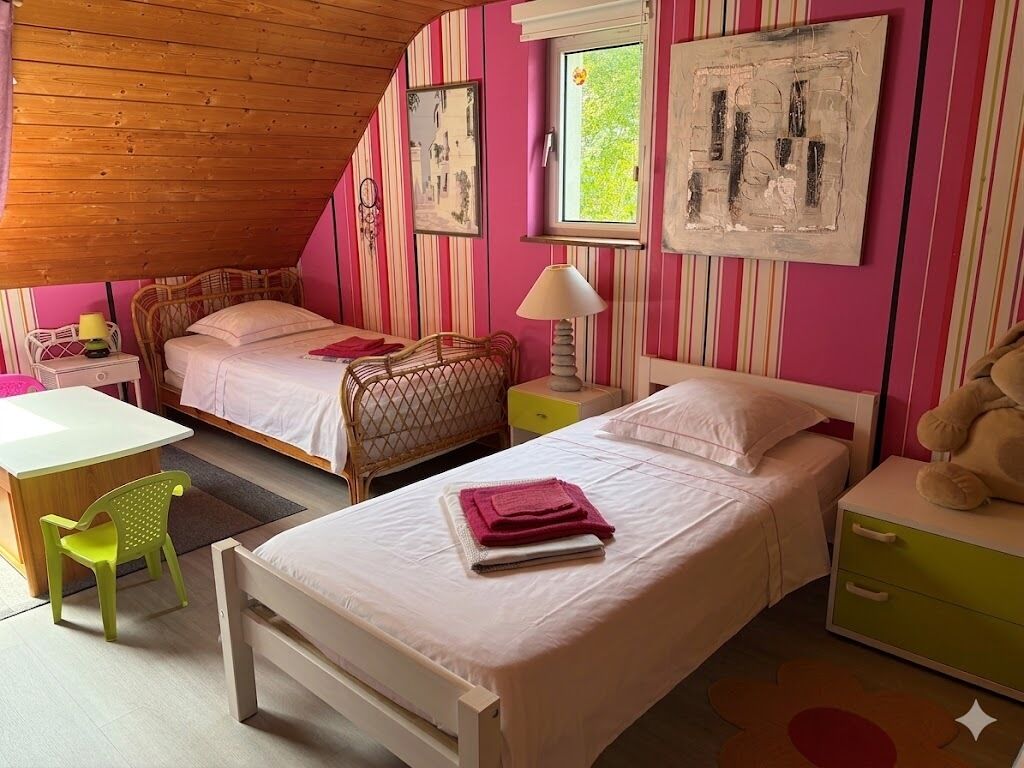 Een slaapkamer met twee bedden, een bureau, een stoel en een raam.