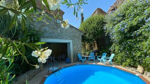 Una piscina con un muro de piedra y sillas azules alrededor.