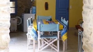 Un comedor rústico con una mesa y sillas de madera, una puerta azul y paredes de piedra.