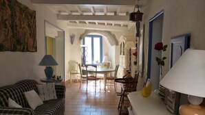 Una sala de estar acogedora con un sofá a rayas, una mesa de comedor con sillas y una zona de cocina con estufa.