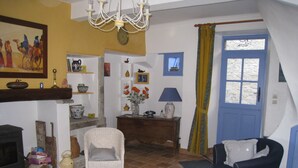 Una sala acogedora con chimenea, una silla de mimbre, un sofá y una mesa de comedor.