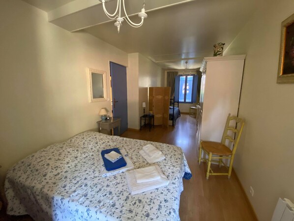 A bedroom with a bed, a chair, a desk, and a wardrobe.