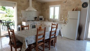 Eine Küche mit Esstisch, Stühlen, Herd, Mikrowelle und Kühlschrank.
