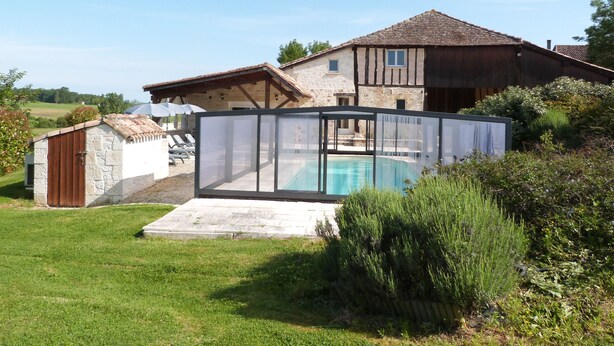 Ein Haus mit Swimmingpool, einem Steinspeicher und einem Holzzaun.