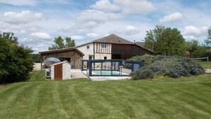 Ein Haus mit großem Garten, Swimmingpool und überdachter Terrasse.