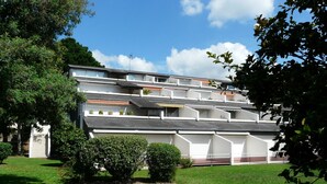 A multi-story building with a modern architectural design, featuring balconies and a well-maintained garden with flowers and shrubs. - Sea view apartment La trinité sur mer (La Trinité-Sur-Mer)