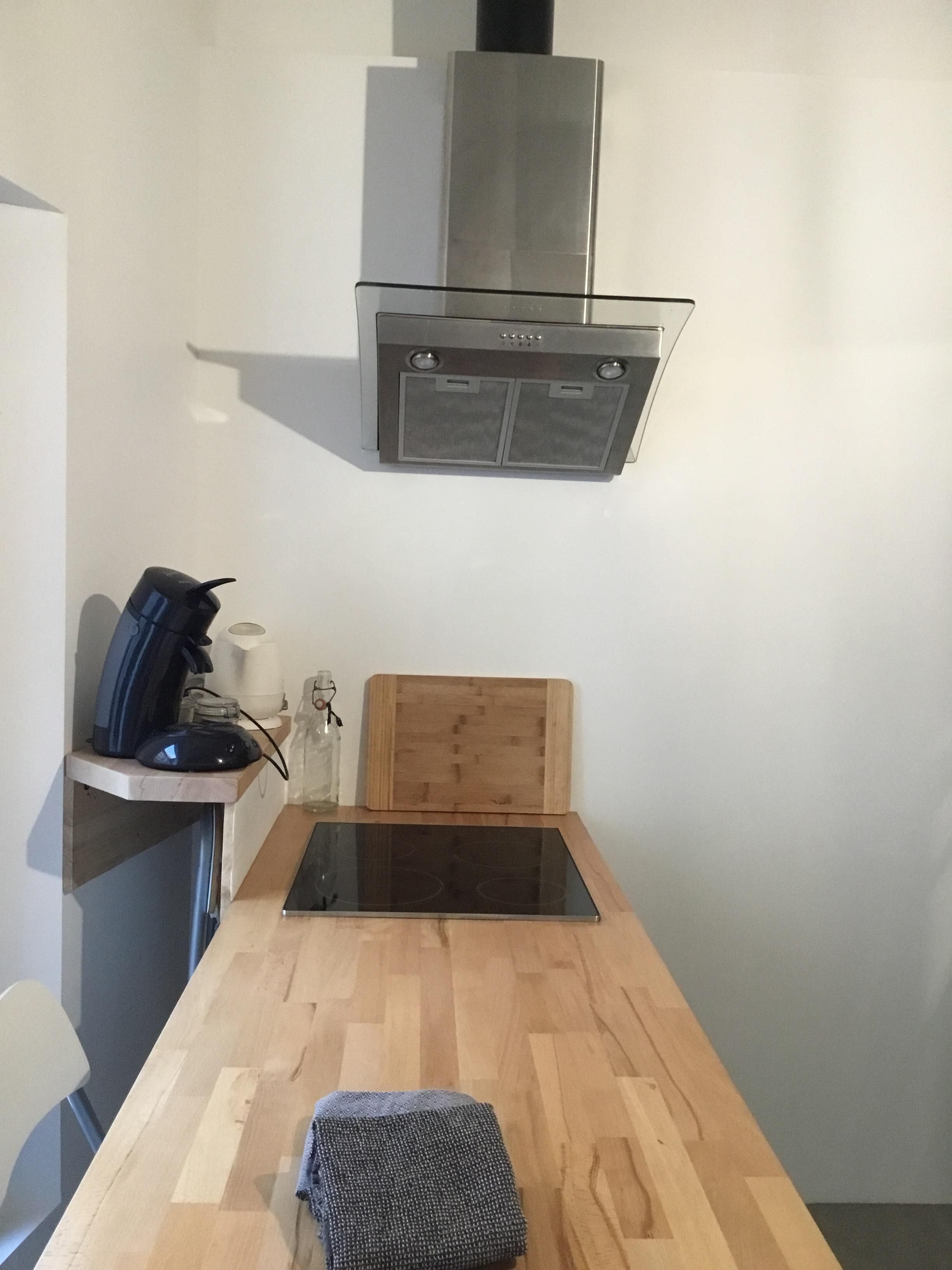 Eine kompakte Küche mit Einbauherd, einer Mikrowelle und einem Holztisch für Schneidearbeiten.