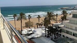 Uitzicht op een strand met palmbomen en parasols vanaf een balkon.