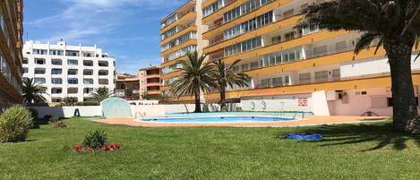 A courtyard with a swimming pool, surrounded by multi-story buildings with balconies.