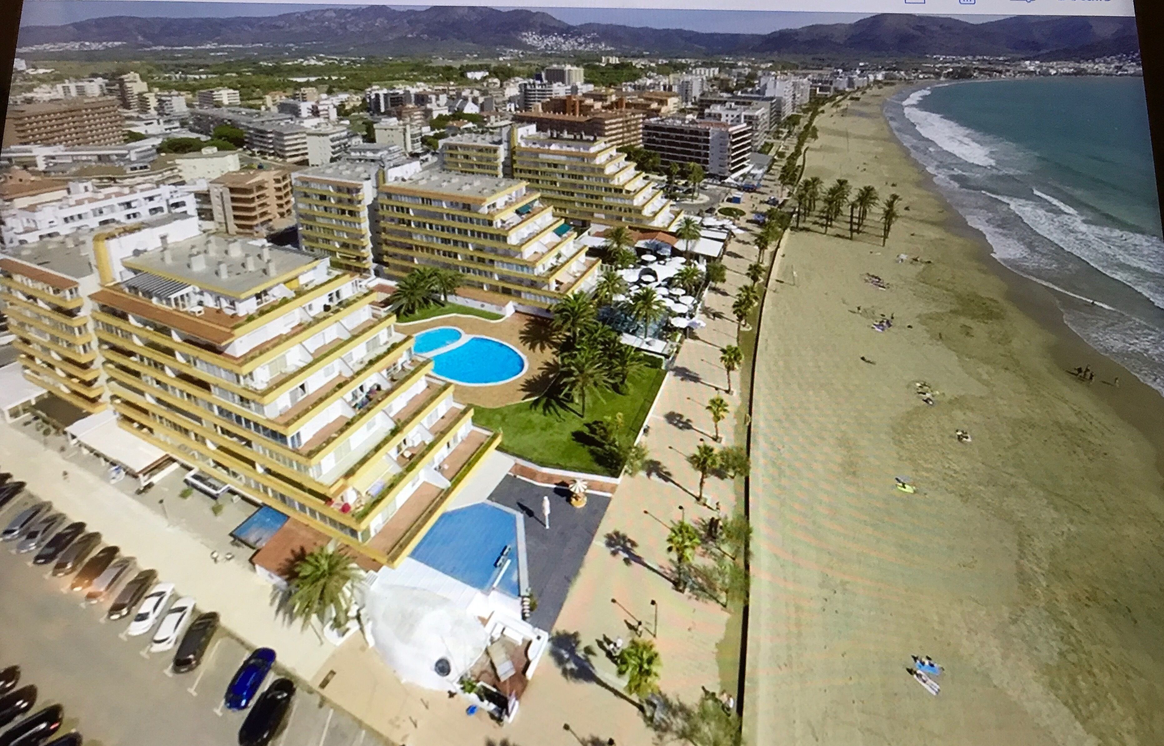 Un hotel frente al mar con varias edificaciones, una playa y una piscina.