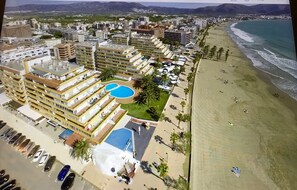 A coastal hotel with multiple buildings, a beach, and a swimming pool.