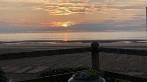 A sunset over a beach with a wooden boardwalk leading to the water. - Typical Norman house on the beach - sea view - big garden - perfect location (Benerville-Sur-Mer)
