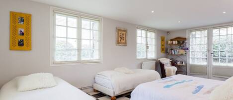 A bedroom with two beds, a radiator, and a bookshelf.