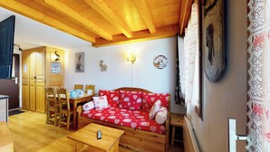A cozy living room with a red sofa, wooden furniture, and a high wooden ceiling. - Duplex, 2 rooms + Cabin in Tignes, ski-in/ski-out, family area (Tignes)