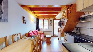 A cozy kitchen with wooden beams, a dining area with a wooden table and chairs, and a kitchen counter with appliances. - Duplex, 2 rooms + Cabin in Tignes, ski-in/ski-out, family area (Tignes)