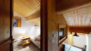 A cozy wooden room with a sloped ceiling, a bed, a bedside table with a lamp, and a window. - Duplex, 2 rooms + Cabin in Tignes, ski-in/ski-out, family area (Tignes)