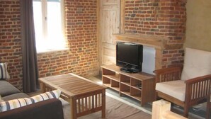 Una sala de estar acogedora con chimenea de ladrillo, muebles de madera y un televisor.