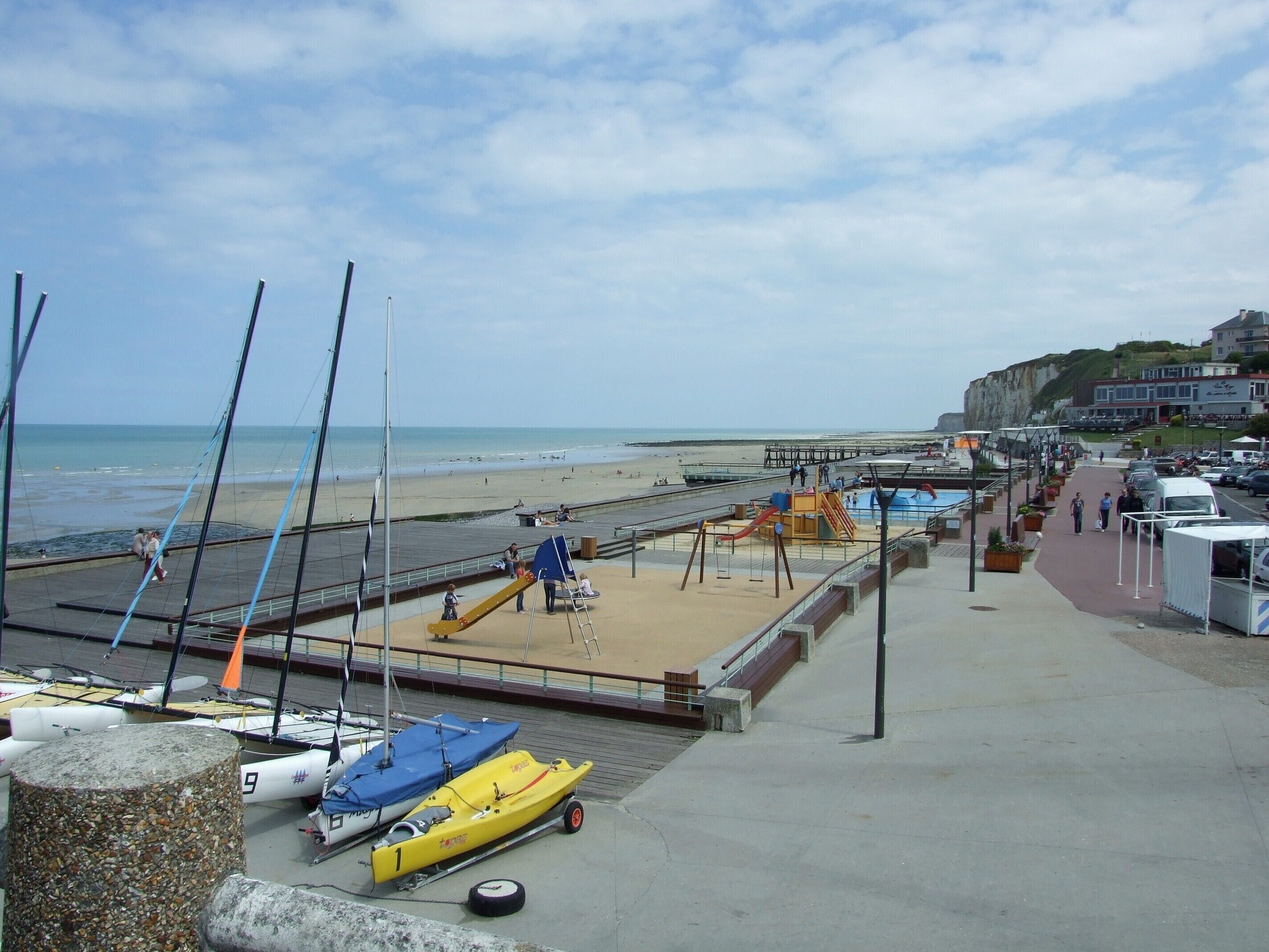 A beachside promenade with a playground, a boat ramp, and a view of the sea.