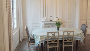 A dining room with a table set for four, flanked by two chairs, a chandelier, and a fireplace with a mantel. - From 98€/jour, 5mns walk to fine sand at M Basse, Jard, 7pers+BB, heating included (Veules-Les-Roses)