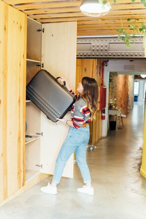 A person carrying a suitcase through a wooden door into a room with a concrete floor and a visible fire extinguisher. - The Loft House Barcelona (Barcelona)